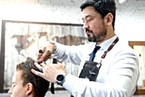 Барбер стрижет волосы клиенту